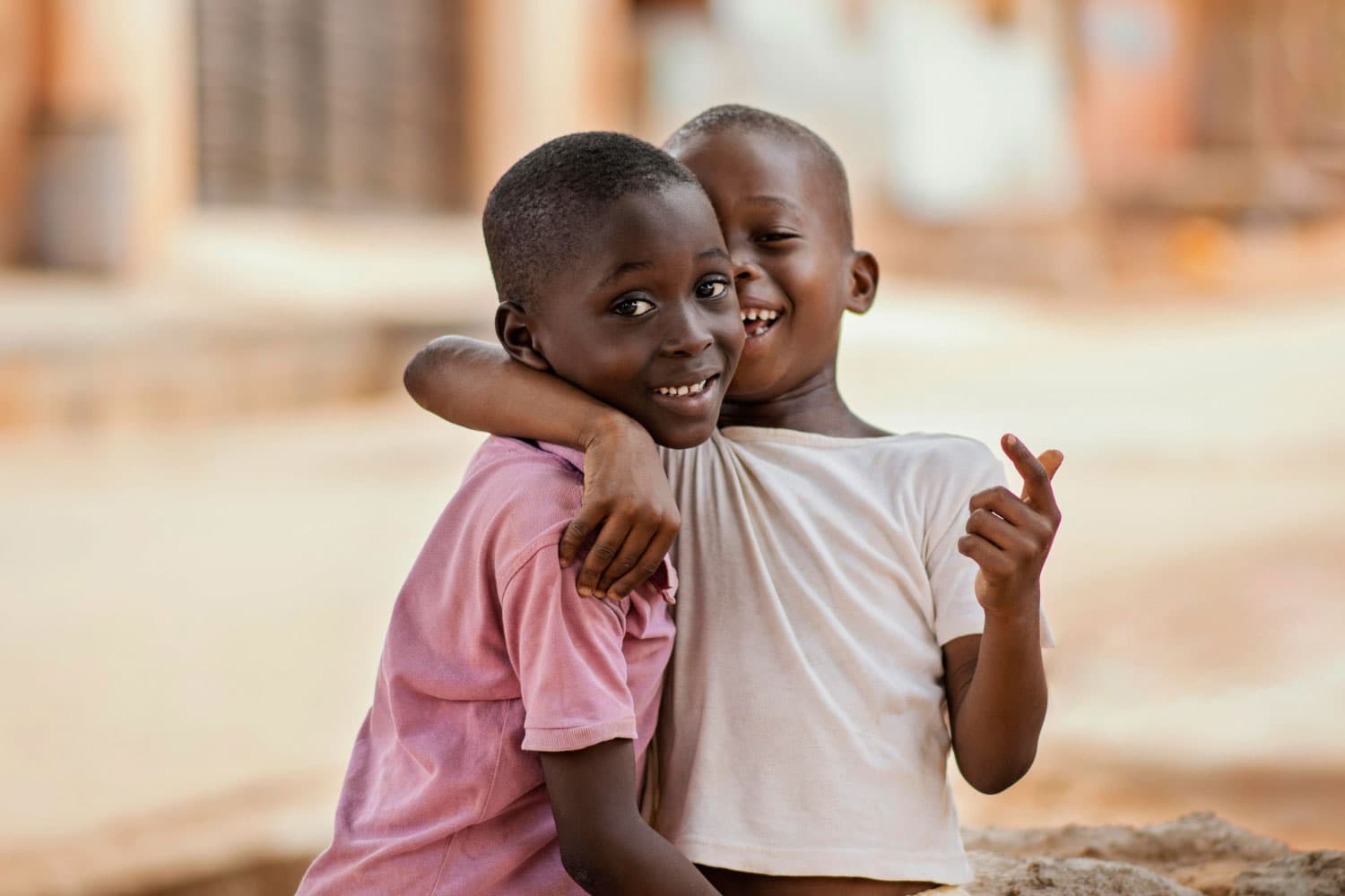 Two children smiling and hugging outdoors